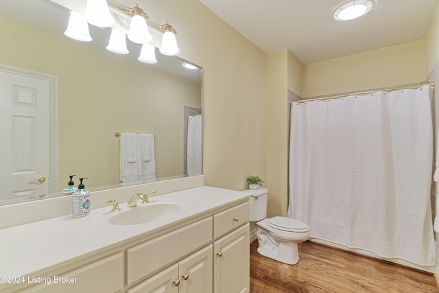 bathroom with toilet, a shower with curtain, vanity, and hardwood / wood-style floors