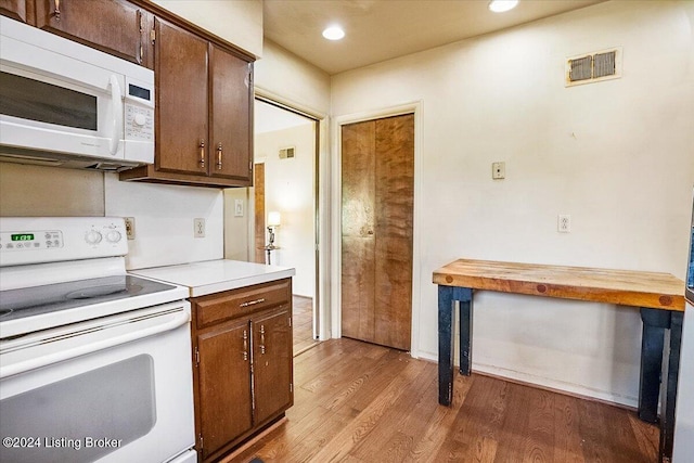 kitchen with hardwood / wood-style floors, white appliances, and butcher block counters