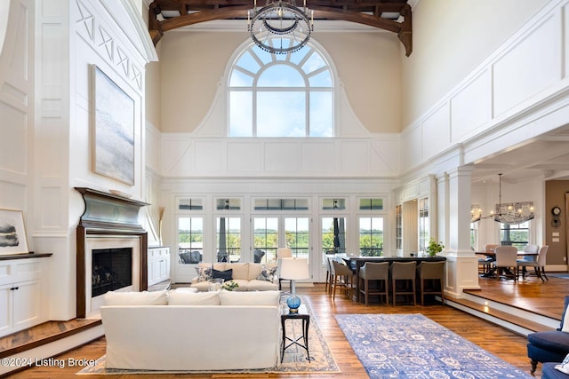 living room featuring a towering ceiling, wood-type flooring, and a notable chandelier