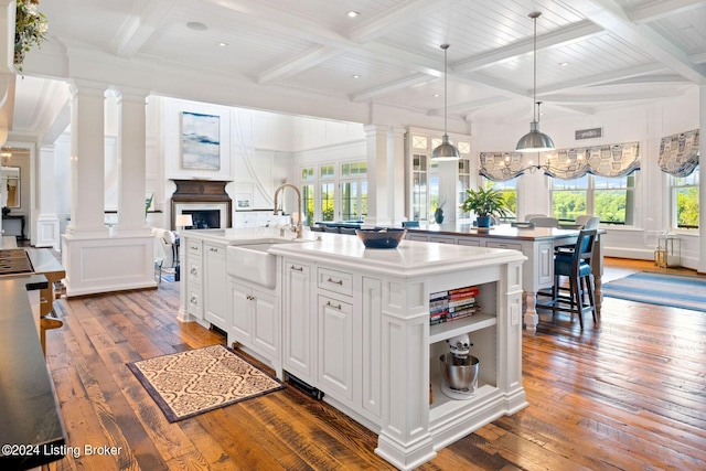 kitchen with white cabinets, dark hardwood / wood-style floors, a kitchen island with sink, and sink