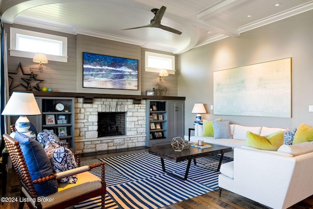 living room with ceiling fan, dark wood-type flooring, a stone fireplace, wooden walls, and ornamental molding