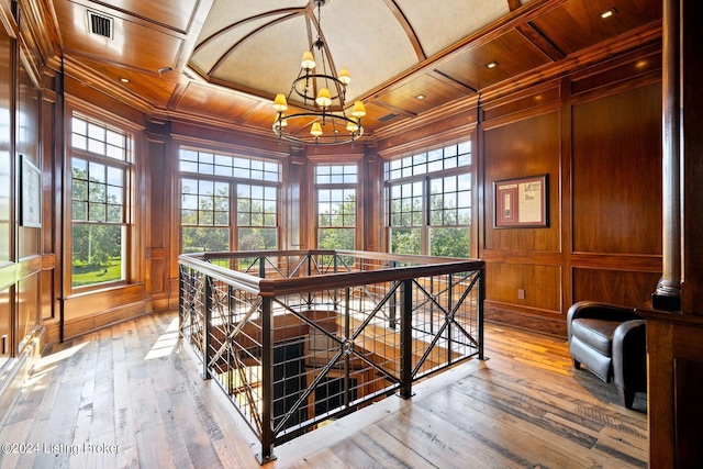 interior space with wood walls, coffered ceiling, wood-type flooring, wood ceiling, and a chandelier