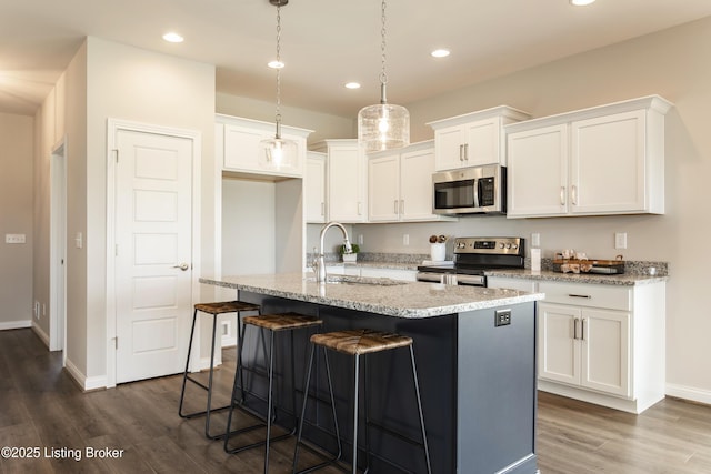 kitchen featuring a center island with sink, sink, decorative light fixtures, white cabinetry, and stainless steel appliances