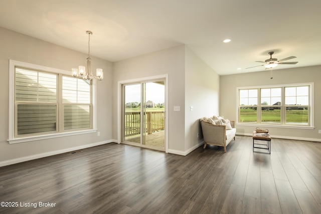 interior space featuring ceiling fan with notable chandelier and dark hardwood / wood-style floors