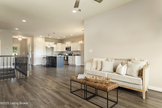 living room with dark hardwood / wood-style flooring, ceiling fan, and sink