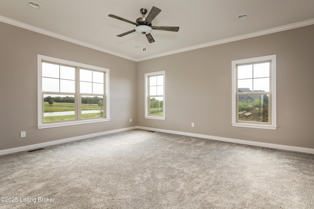 empty room with ornamental molding, carpet floors, ceiling fan, and a healthy amount of sunlight