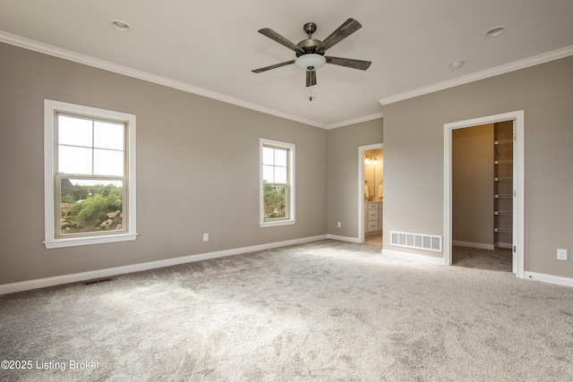 unfurnished bedroom with light carpet, ceiling fan, crown molding, a spacious closet, and connected bathroom