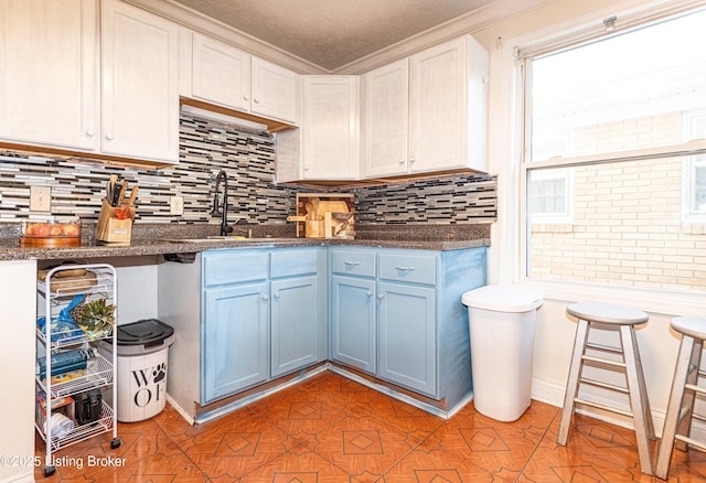 kitchen featuring sink, blue cabinets, white cabinets, dark stone countertops, and tasteful backsplash