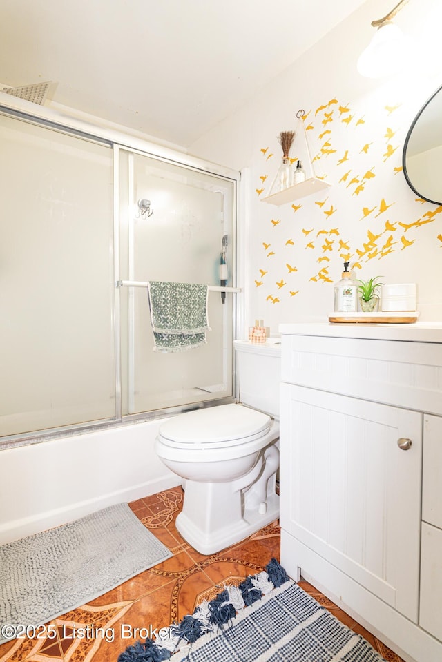 full bathroom with combined bath / shower with glass door, tile patterned flooring, vanity, and toilet