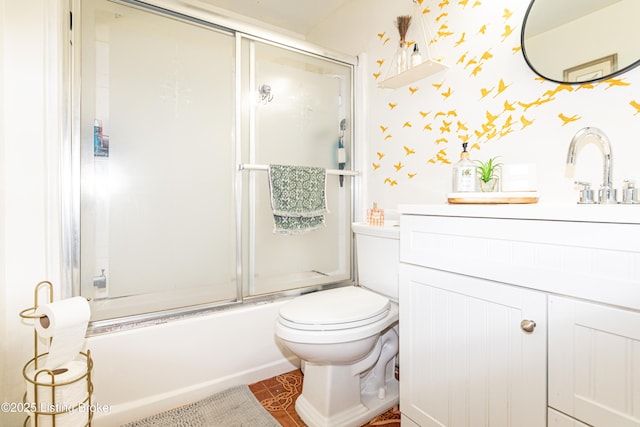 full bathroom featuring vanity, combined bath / shower with glass door, and toilet