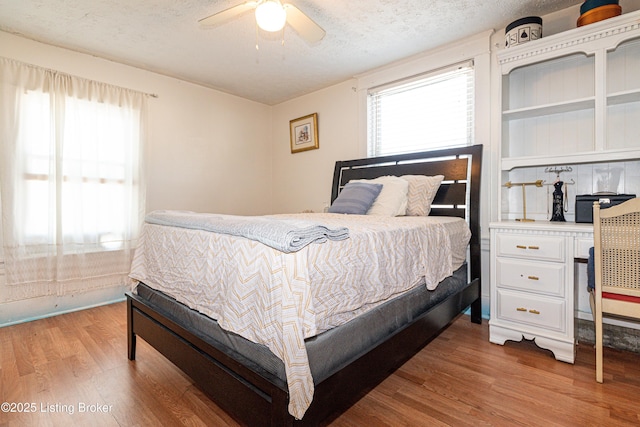 bedroom with a textured ceiling, ceiling fan, and hardwood / wood-style flooring