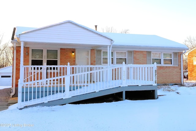 snow covered back of property with covered porch