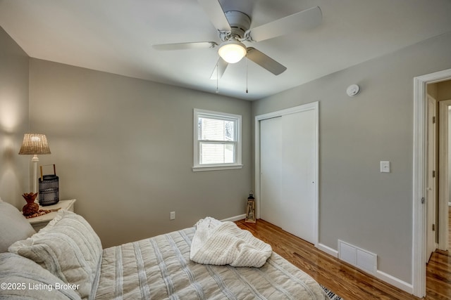 bedroom featuring a closet, visible vents, a ceiling fan, wood finished floors, and baseboards