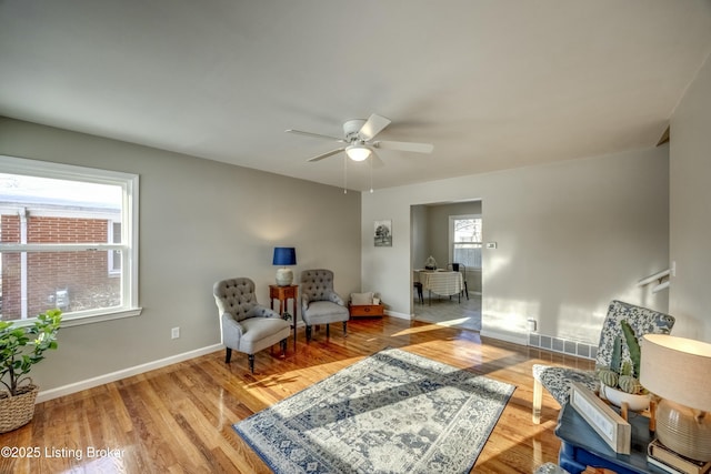 living area with a ceiling fan, baseboards, and wood finished floors