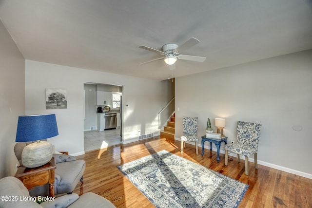 sitting room with stairway, light wood-type flooring, visible vents, and baseboards