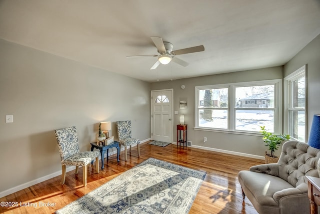 sitting room with baseboards, wood finished floors, and a healthy amount of sunlight