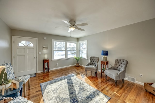 sitting room with ceiling fan, light wood-type flooring, visible vents, and baseboards