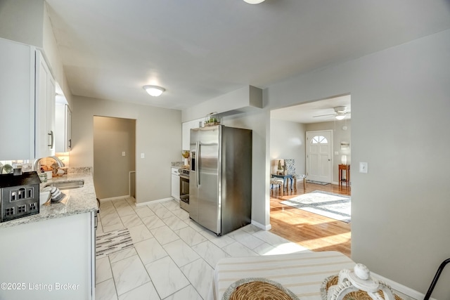 kitchen with white cabinets, light stone counters, marble finish floor, stainless steel appliances, and a sink