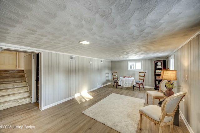 sitting room featuring baseboards, stairway, visible vents, and light wood-style floors