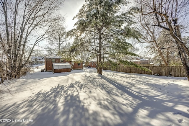 snowy yard with a jacuzzi and fence