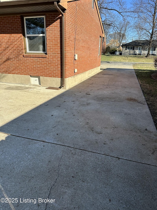 view of side of home featuring brick siding and driveway