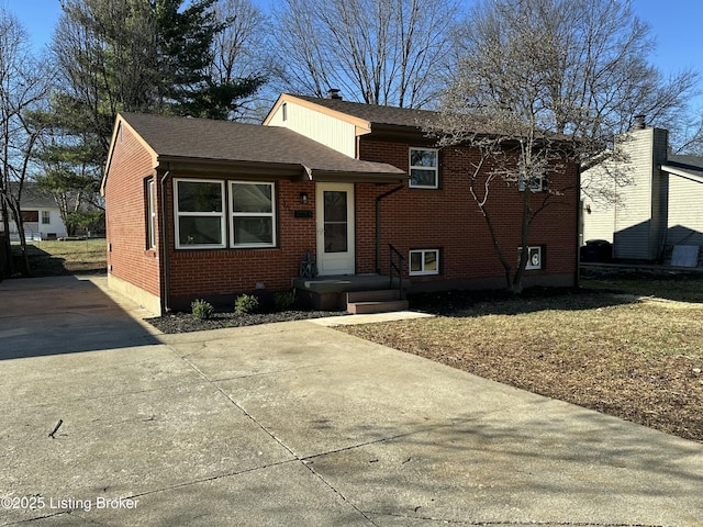 split level home featuring brick siding and a shingled roof