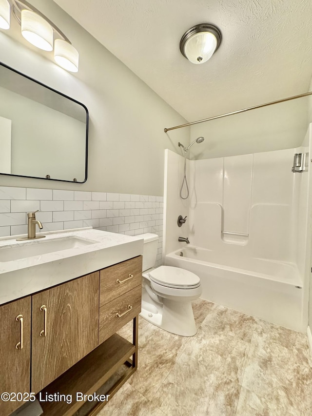 full bathroom featuring toilet, vanity, tile walls, and tub / shower combination