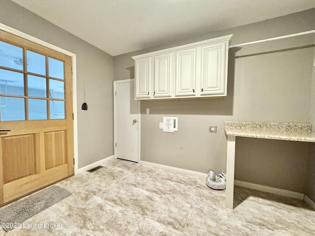 clothes washing area featuring electric dryer hookup and cabinets