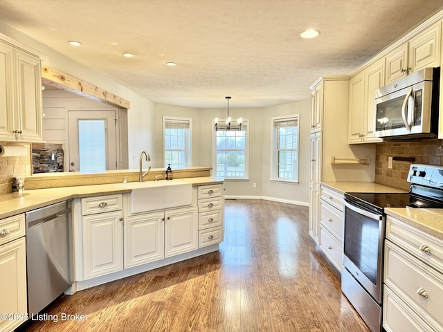 kitchen featuring decorative backsplash, appliances with stainless steel finishes, sink, a chandelier, and hanging light fixtures