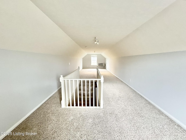 additional living space with a wall mounted air conditioner, carpet, and vaulted ceiling