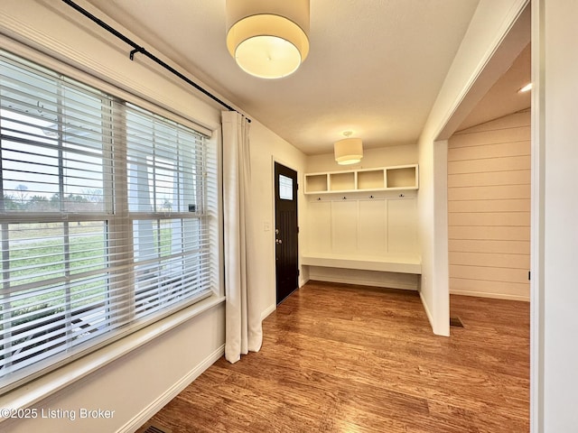 mudroom featuring hardwood / wood-style flooring and wooden walls