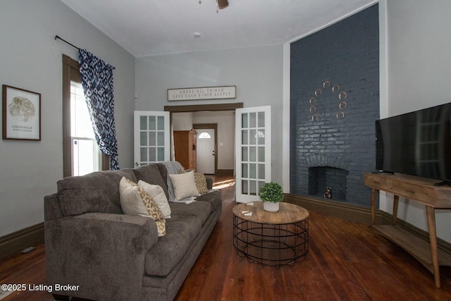 living room featuring ceiling fan, a brick fireplace, dark hardwood / wood-style flooring, and french doors