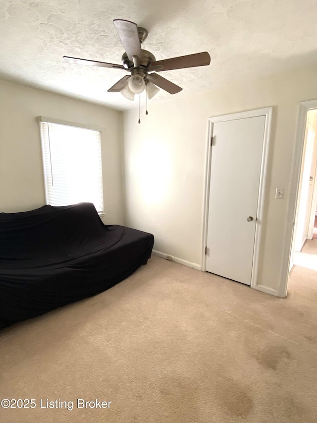 bedroom featuring ceiling fan, light colored carpet, and a textured ceiling