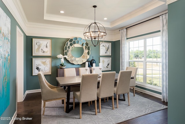 dining space featuring a tray ceiling, crown molding, an inviting chandelier, and hardwood / wood-style flooring