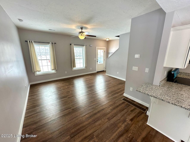 unfurnished living room featuring a textured ceiling, dark hardwood / wood-style floors, and ceiling fan