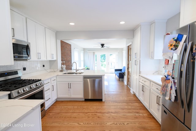 kitchen with white cabinetry, sink, french doors, kitchen peninsula, and appliances with stainless steel finishes