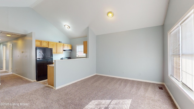 kitchen with black refrigerator, light colored carpet, light brown cabinets, and lofted ceiling