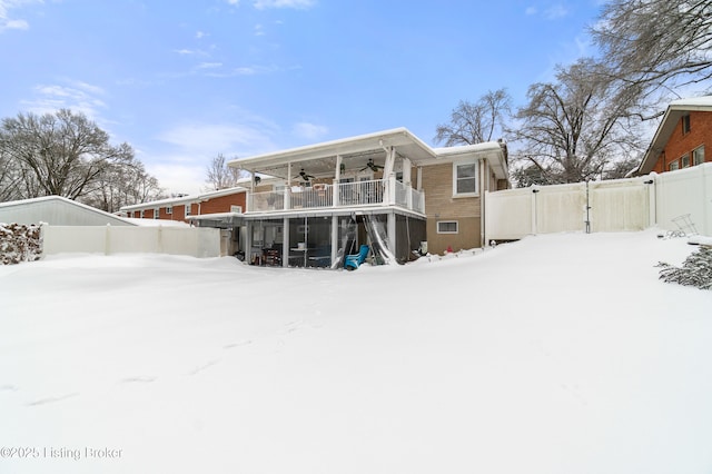 snow covered house featuring ceiling fan and a balcony