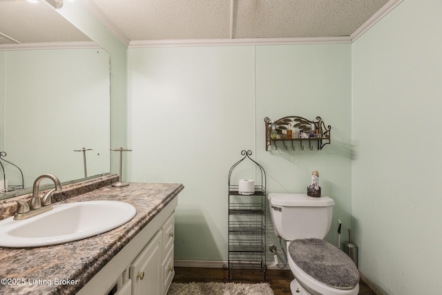 bathroom featuring a textured ceiling, crown molding, vanity, and toilet