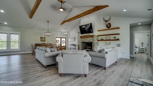 living room with beamed ceiling, light wood-type flooring, ceiling fan, high vaulted ceiling, and a stone fireplace