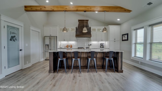 kitchen with a large island, a breakfast bar area, lofted ceiling with beams, high end refrigerator, and tasteful backsplash