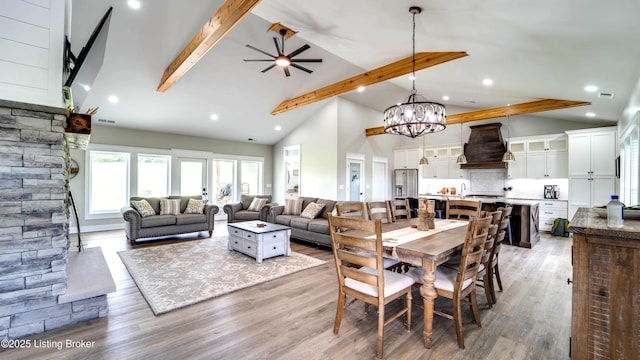 dining area featuring ceiling fan with notable chandelier, high vaulted ceiling, wood-type flooring, and beamed ceiling