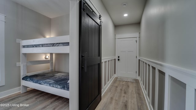 corridor with light wood-type flooring and a barn door