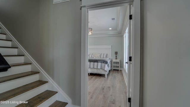 corridor with ornamental molding and light hardwood / wood-style floors