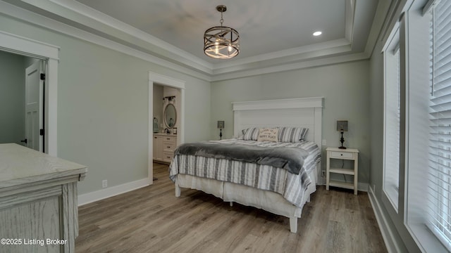 bedroom featuring a tray ceiling, light hardwood / wood-style flooring, a chandelier, and multiple windows