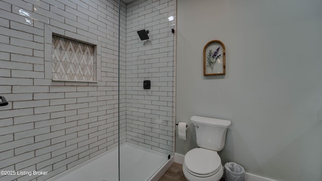 bathroom with a tile shower and toilet