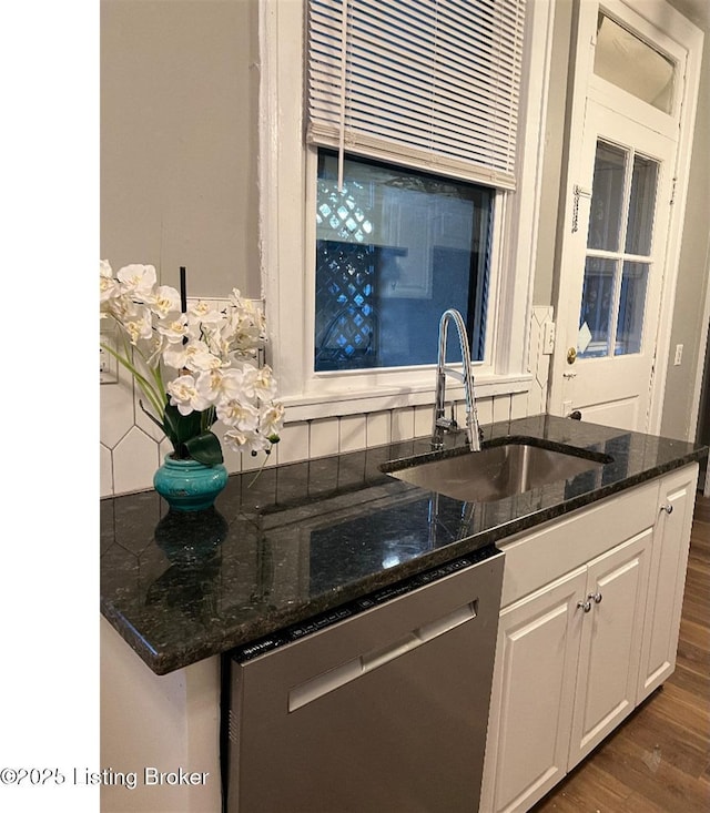 kitchen featuring dark hardwood / wood-style flooring, sink, dark stone countertops, dishwasher, and white cabinetry