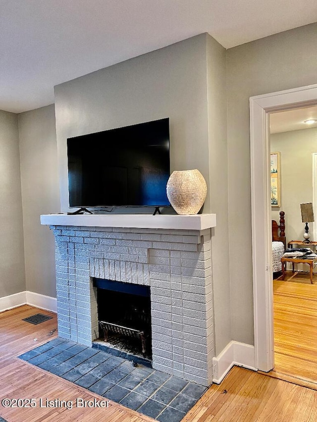 room details featuring wood-type flooring and a brick fireplace