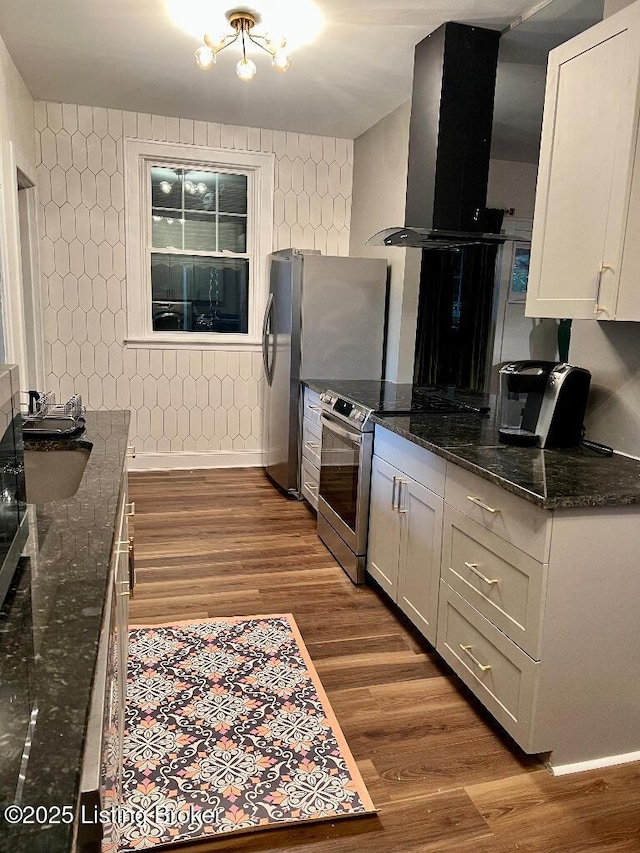 kitchen with dark stone countertops, wood-type flooring, extractor fan, and appliances with stainless steel finishes