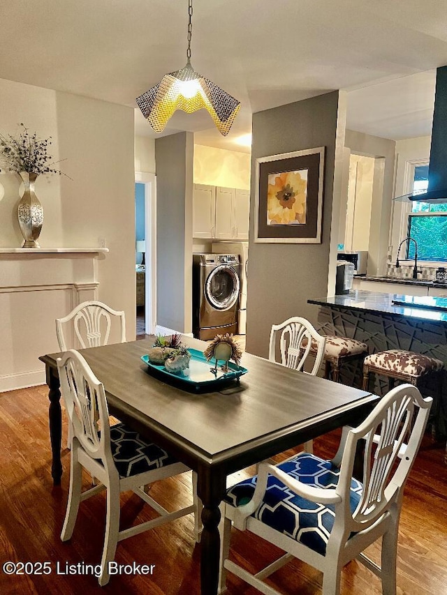 dining room with hardwood / wood-style floors, washing machine and dryer, and sink